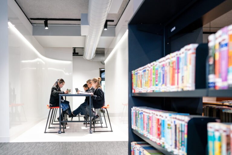 Primary students reading together surrounded by floor-to-ceiling whiteboard walls.