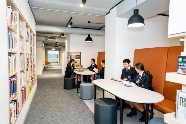 Students scattered along tables in study areas.